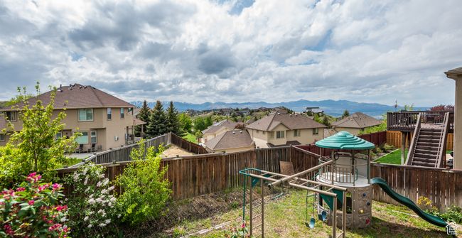 Fenced backyard featuring a playground, a residential view, and a mountain view | Image 36