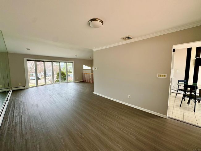 Unfurnished living room with baseboards, ornamental molding, visible vents, and dark wood finished floors | Image 5