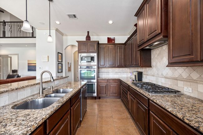 Another look at the kitchen that features a gas cook top and double ovens. | Image 16