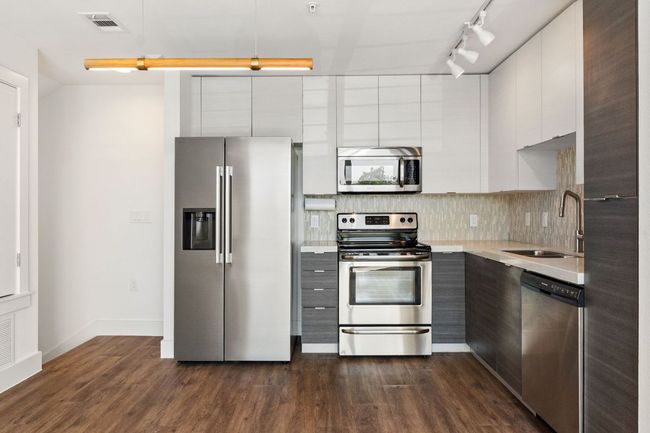 Streamlined cooking space with stainless range, microwave, and easy-care quartz surfaces. | Image 17