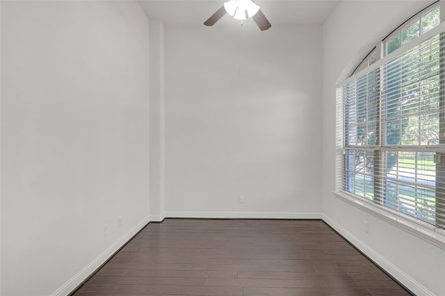 Empty room with dark wood-style floors and a ceiling fan | Image 7