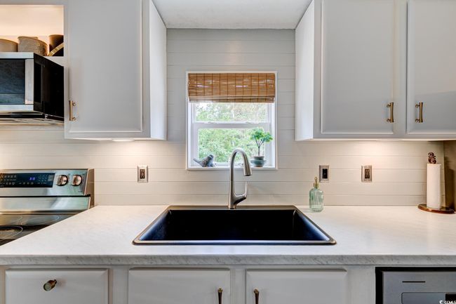 Kitchen with a sink, electric stove, white cabinets, and light countertops | Image 13