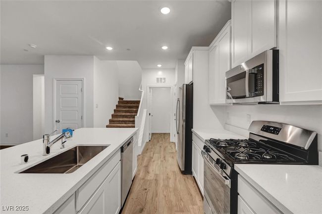 Kitchen featuring recessed lighting, a sink, light wood-style flooring, white cabinetry, and appliances with stainless steel finishes | Image 17