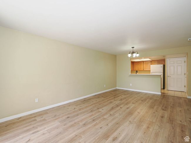 Unfurnished living room with light wood finished floors, baseboards, and an inviting chandelier | Image 6