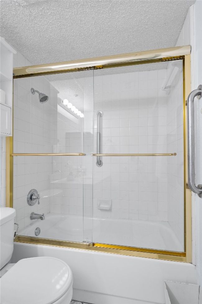 Full bath featuring toilet, a textured ceiling, and bath / shower combo with glass door | Image 29