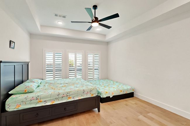 Bedroom featuring a raised ceiling, wood finished floors, baseboards, recessed lighting, and ceiling fan | Image 19