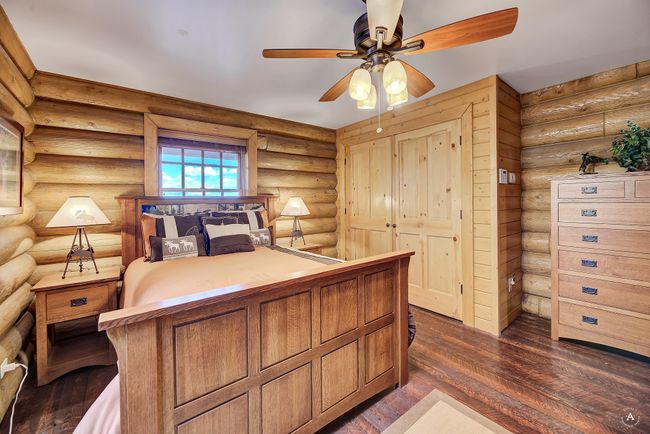 Bedroom featuring log walls, dark wood-style flooring, and a ceiling fan | Image 18