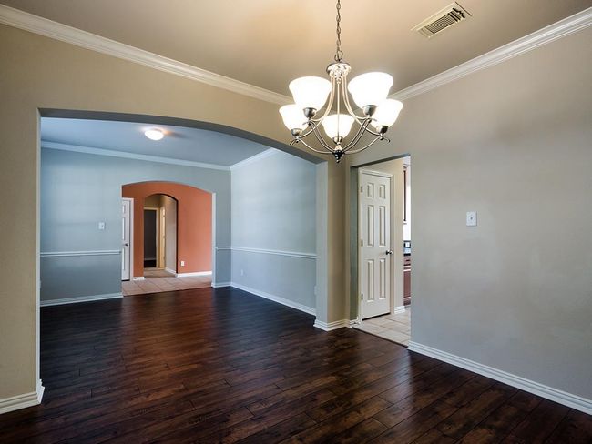 Empty room featuring arched walkways, wood-type flooring, a chandelier, crown molding, and baseboards | Image 14