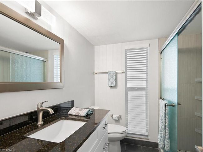 remodeled guest bathroom with toilet, a stall shower, vanity, and tile patterned flooring | Image 12