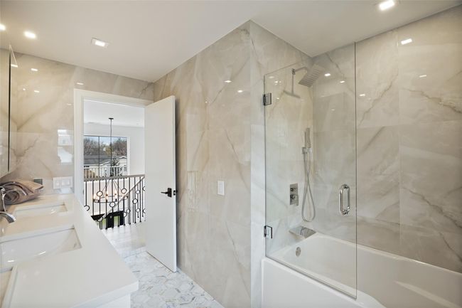 Full bath with double vanity, tile walls, enclosed tub / shower combo, and a sink | Image 24