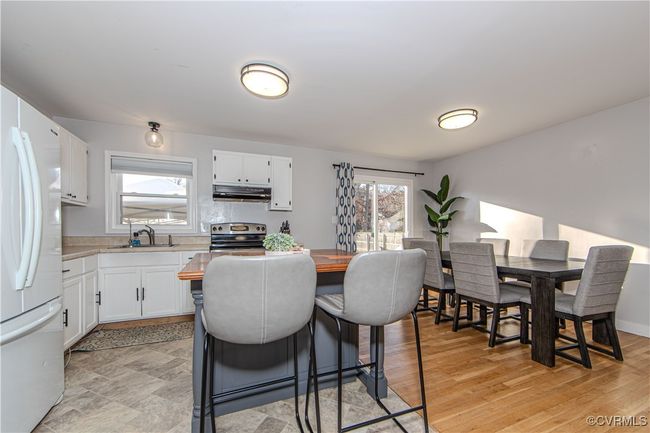 Kitchen with stainless steel range with electric stovetop, white cabinets, white refrigerator, sink, and a healthy amount of sunlight | Image 13