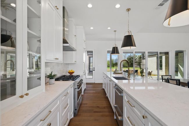Kitchen with dark wood-type flooring, decorative backsplash, a sink, visible vents, and appliances with stainless steel finishes | Image 9