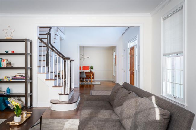 Living room with dark hardwood flooring, molding, stairway. | Image 4