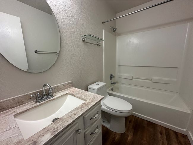 Full bath with a textured wall, wood finished floors, vanity, and shower / bathtub combination | Image 25