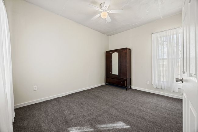 Spare room featuring a ceiling fan, dark colored carpet, and baseboards | Image 17