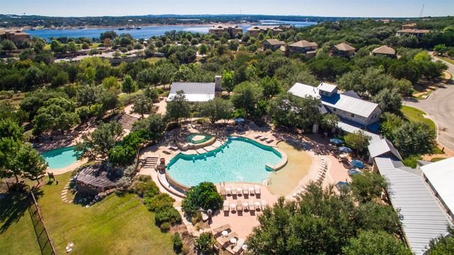 Aerial view of The Hollows' resort-style community pool complex, featuring a large, lagoon-like pool. The amenities include a private resort-style bar & grill, a covered pavilion, BBQ grills, and smokers, creating a perfect setting for gatherings. Scenic lake views add to the relaxing ambiance. | Image 40