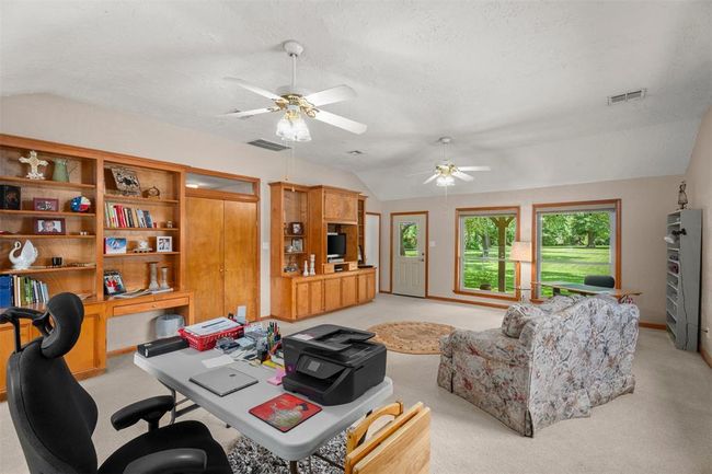 Spacious multipurpose room with ample natural light, featuring a cozy seating area, built-in shelving, and multiple workstations. Ideal for a home office or second living space. A great mother in-law quarters. | Image 14
