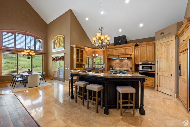 Kitchen featuring a chandelier, high vaulted ceiling, a warming drawer, stainless steel oven, and dark stone counters | Image 28