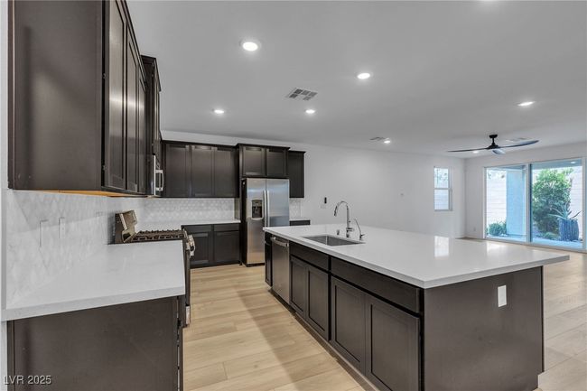 Kitchen featuring a sink, stainless steel appliances, decorative backsplash, recessed lighting, and light countertops | Image 5
