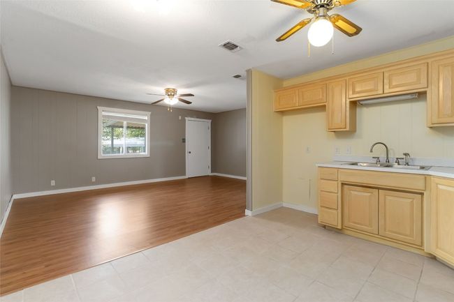 Kitchen with light countertops, light brown cabinetry, a sink, visible vents, and a ceiling fan | Image 12