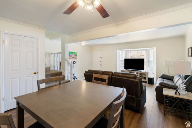 Dining area featuring dark wood-style floors, crown molding, a ceiling fan, and stairs | Image 6