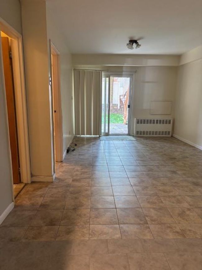 Tiled empty room with radiator and baseboards | Image 5