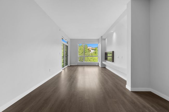 Unfurnished living room featuring dark wood-style flooring, baseboards, and a baseboard radiator | Image 22