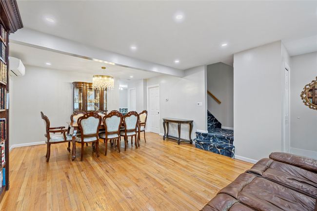 Dining room featuring light wood finished floors, an AC wall unit, recessed lighting, a notable chandelier, and stairs | Image 7