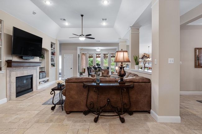 Great room featuring stone tile floors, built in shelves, fireplace, and recessed lighting | Image 6