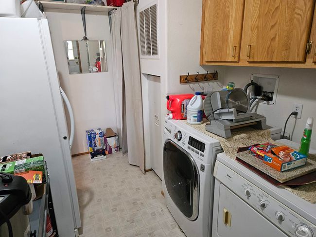 Washroom featuring washer and dryer, cabinet space, a heating unit, and light flooring | Image 6