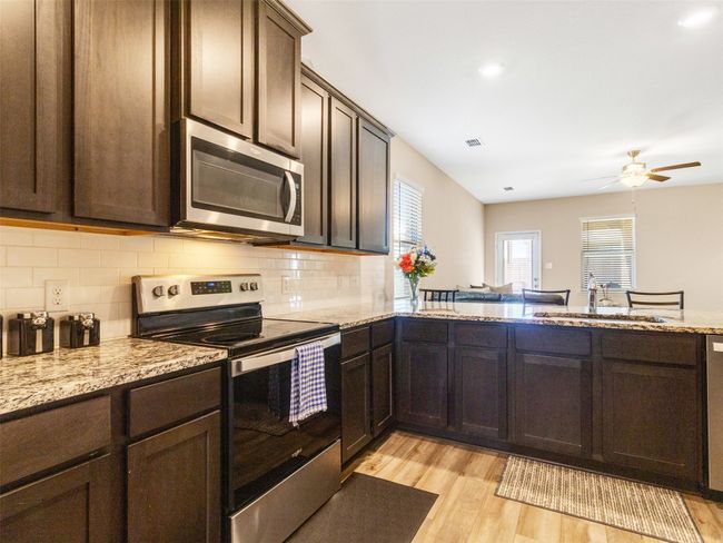 Kitchen featuring sink, backsplash, stainless steel appliances, and light hardwood / wood-style floors | Image 7