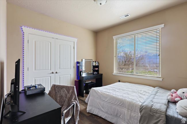 Bedroom with a closet, dark wood-style flooring, and visible vents | Image 14