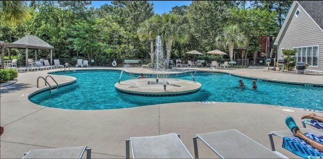 Community pool with a gazebo, a patio area, and view of wooded area | Image 23