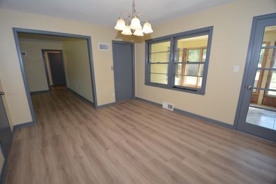 Unfurnished dining area featuring a notable chandelier and light wood-type flooring | Image 3