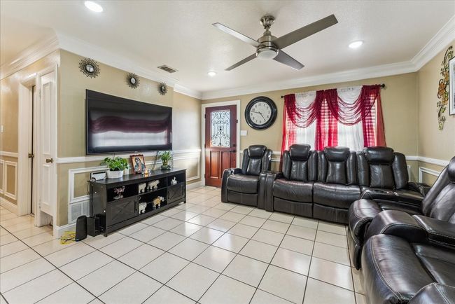 Cinema room with ornamental molding, light tile patterned floors, and a ceiling fan | Image 19