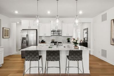 (Photo of a decorated model, actual homes finishes will vary) The spacious kitchen feature a large center island, quartz countertops, LVP floors, stainless appliances and more! | Image 2