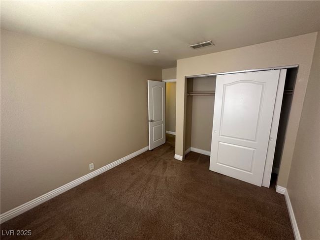 Unfurnished bedroom with a closet, visible vents, dark colored carpet, and baseboards | Image 16