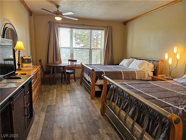 Bedroom with dark wood-type flooring, crown molding, and a textured ceiling | Image 16