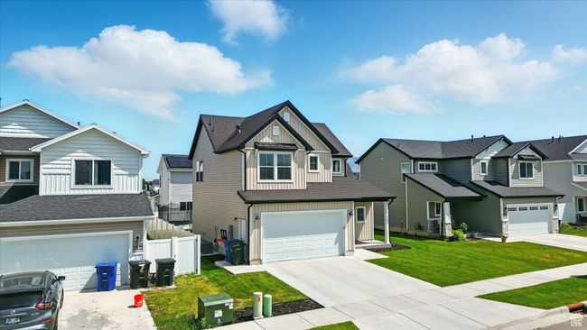 View of front facade with board and batten siding, a residential view, a garage, and driveway | Image 23