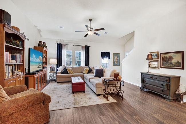 Living room featuring ceiling fan, baseboards, visible vents, and wood finished floors | Image 13
