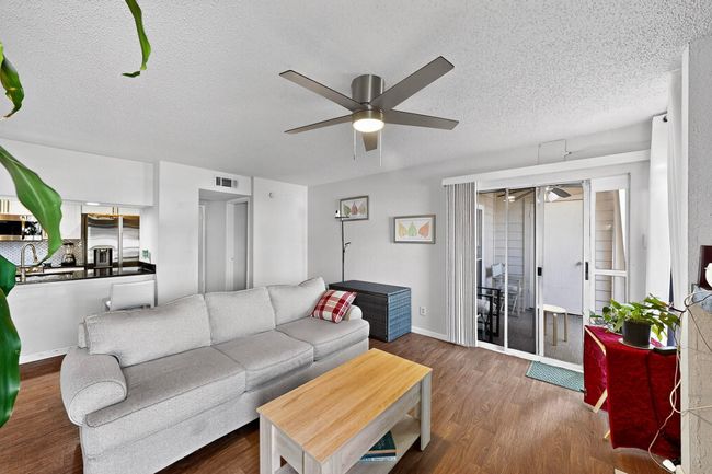 Living area featuring ceiling fan, wood finished floors, and a textured ceiling | Image 6