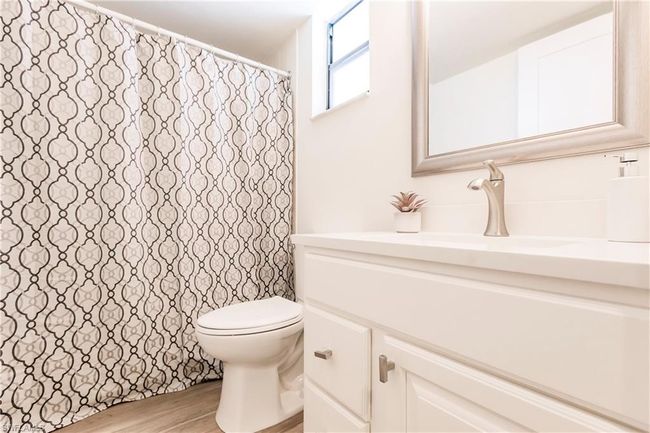 Bathroom with wood finished floors, toilet, vanity, and a shower with curtain | Image 21
