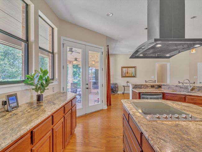 Kitchen featuring a sink, black electric cooktop, french doors, island range hood, and light wood-style flooring | Image 13