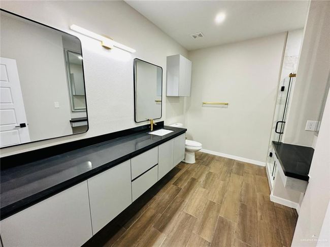 Bathroom with a shower stall, toilet, wood finished floors, vanity, and baseboards | Image 8