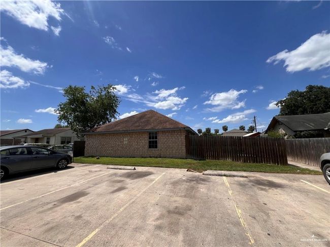 View of side of home with uncovered parking, fence, and a lawn | Image 11