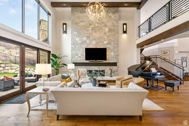 Living area featuring a high ceiling, wood-type flooring, a notable chandelier, and stairs | Image 22