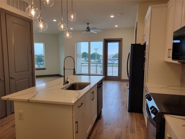 Kitchen featuring light wood-style floors, a kitchen island with sink, white cabinetry, and recessed lighting | Image 7