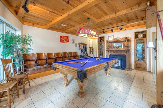 Game room with track lighting, a wood ceiling with exposed beams, light tile patterned flooring, a fireplace, and billiards table | Image 35