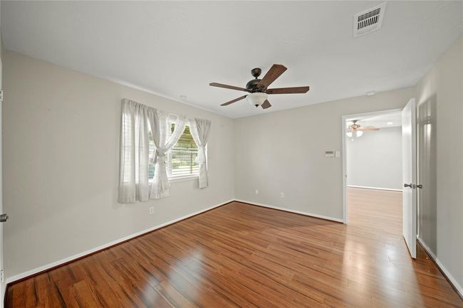 The primary bedroom features wood vinyl floors, a ceiling fan, and a large window with a view of the backyard. It includes an en-suite bathroom and a walk in closed. | Image 18