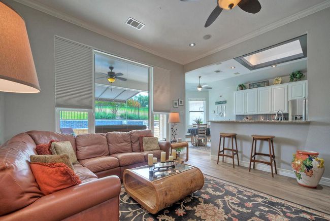 Living room featuring visible vents, a ceiling fan, crown molding, and light wood finished floors | Image 15